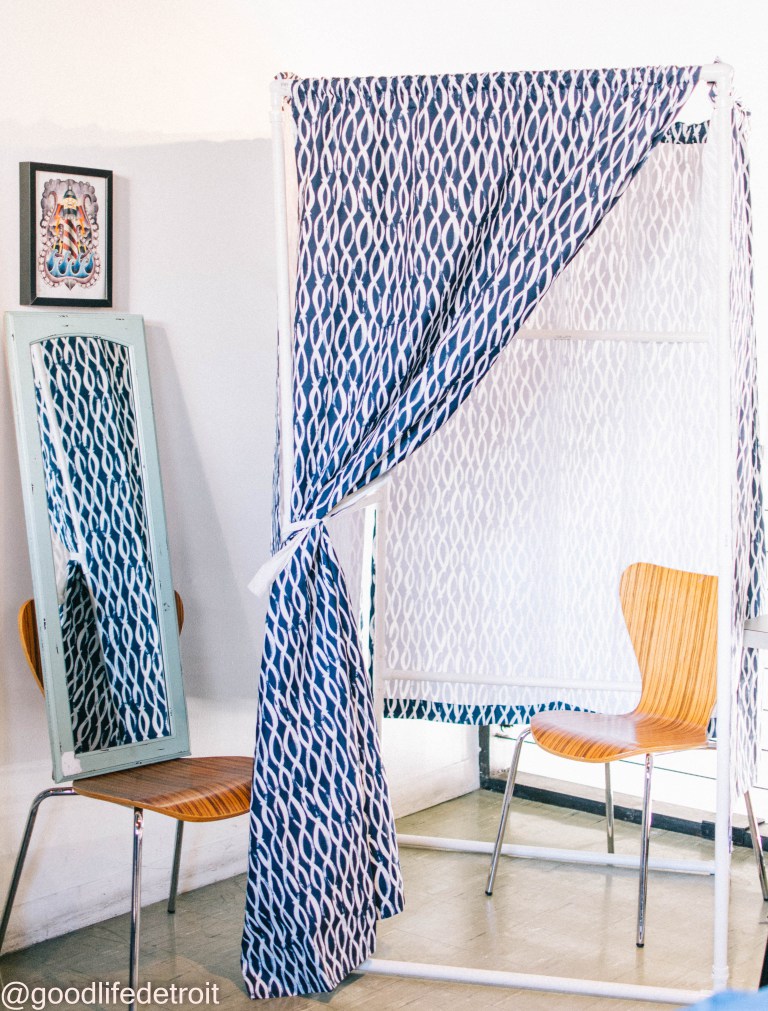A home-made stand up dressing room made from white PVC piping and a blue patterned curtain.